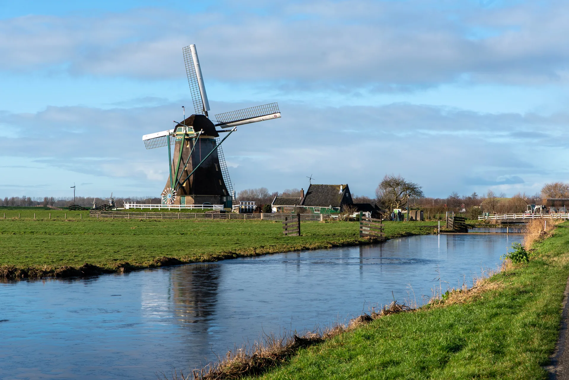 A traditional Dutch windmill beside a canal in a green polder landscape